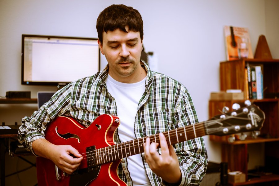 Sam playing a red hollow-body guitar